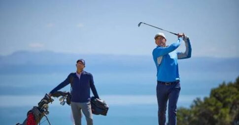 KJUSのゴルフウェアで海沿いのコースをラウンドする男性ゴルファー