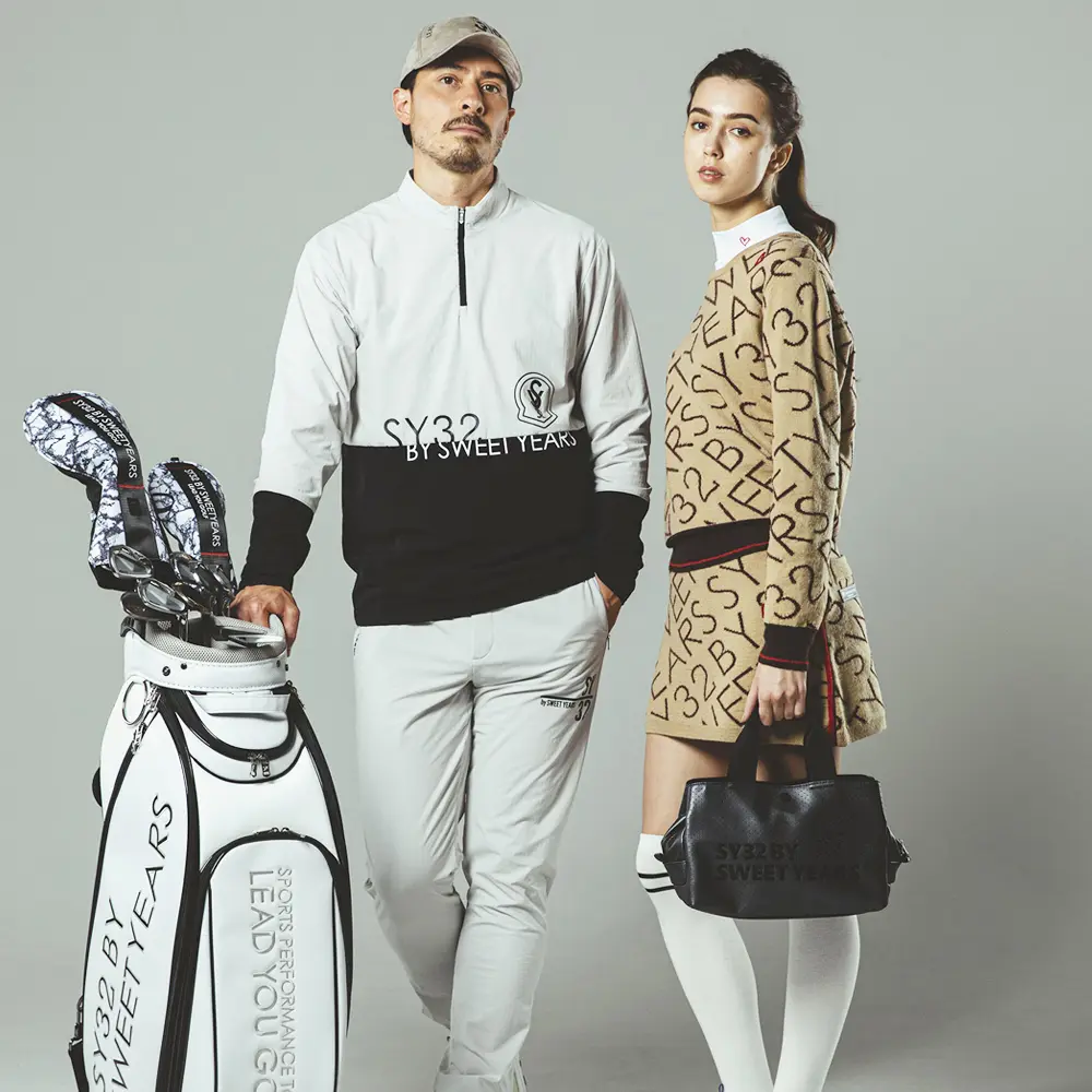 SY32 by SWEET YEARS GOLFのウェアを着用しゴルフバッグと立つ男女モデル