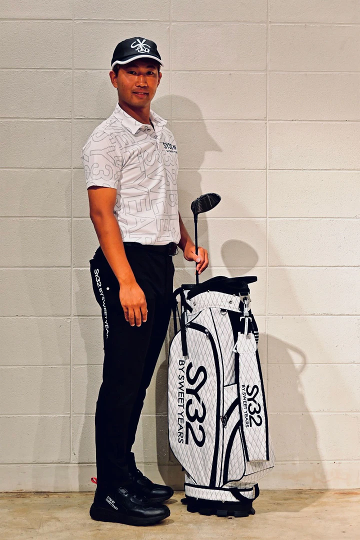 SY32 GOLFのウェアを着用しキャディバッグと立つ徳光祐哉