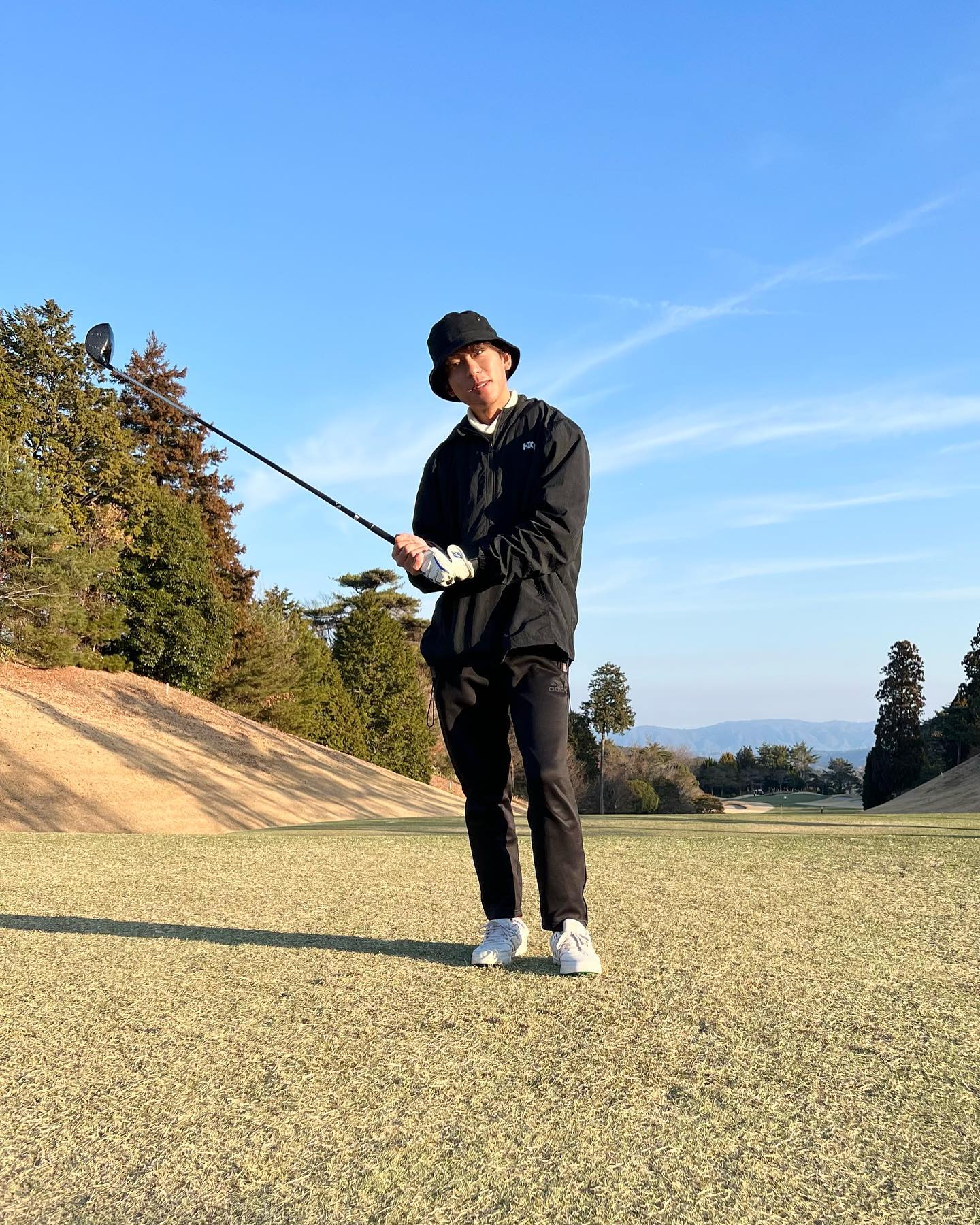 黒のフーディーと細身パンツを合わせたメンズ冬ゴルフコーデ